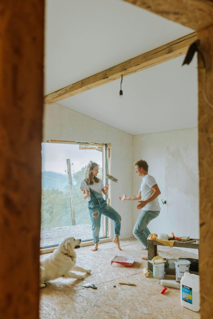 Joyful couple dancing during home renovation with their dog.